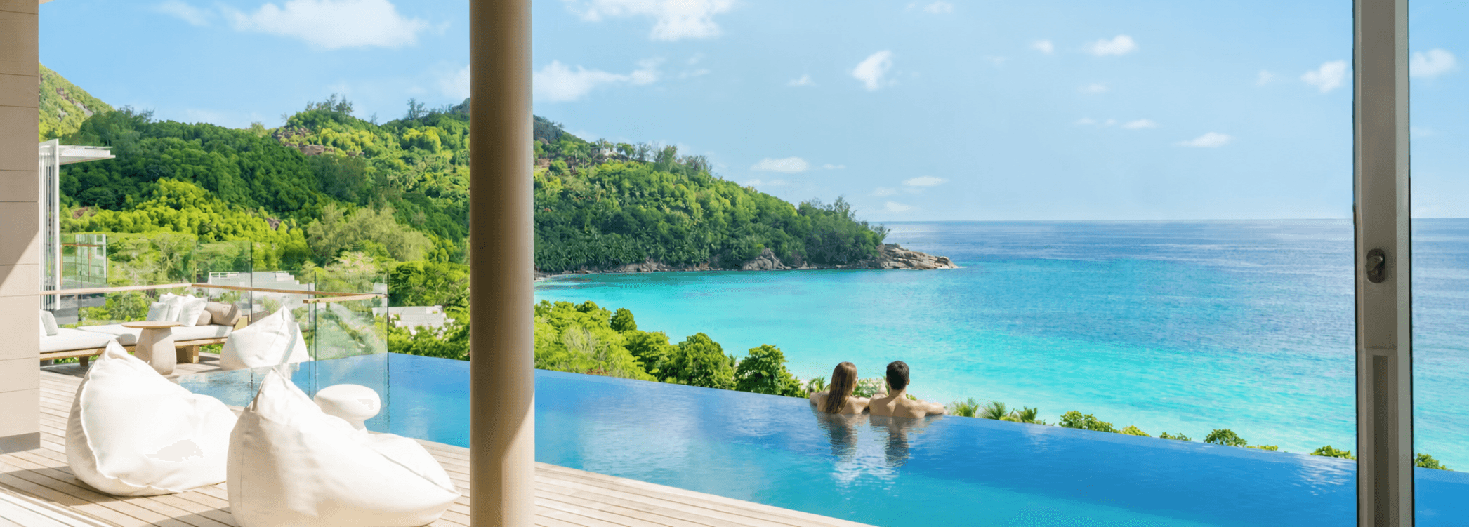 Couple enjoying a hotel infinity pool above a tropical bay